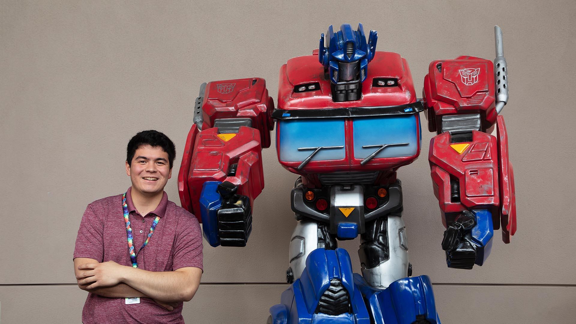 Andrew Baxter posing with a transformer like figure.